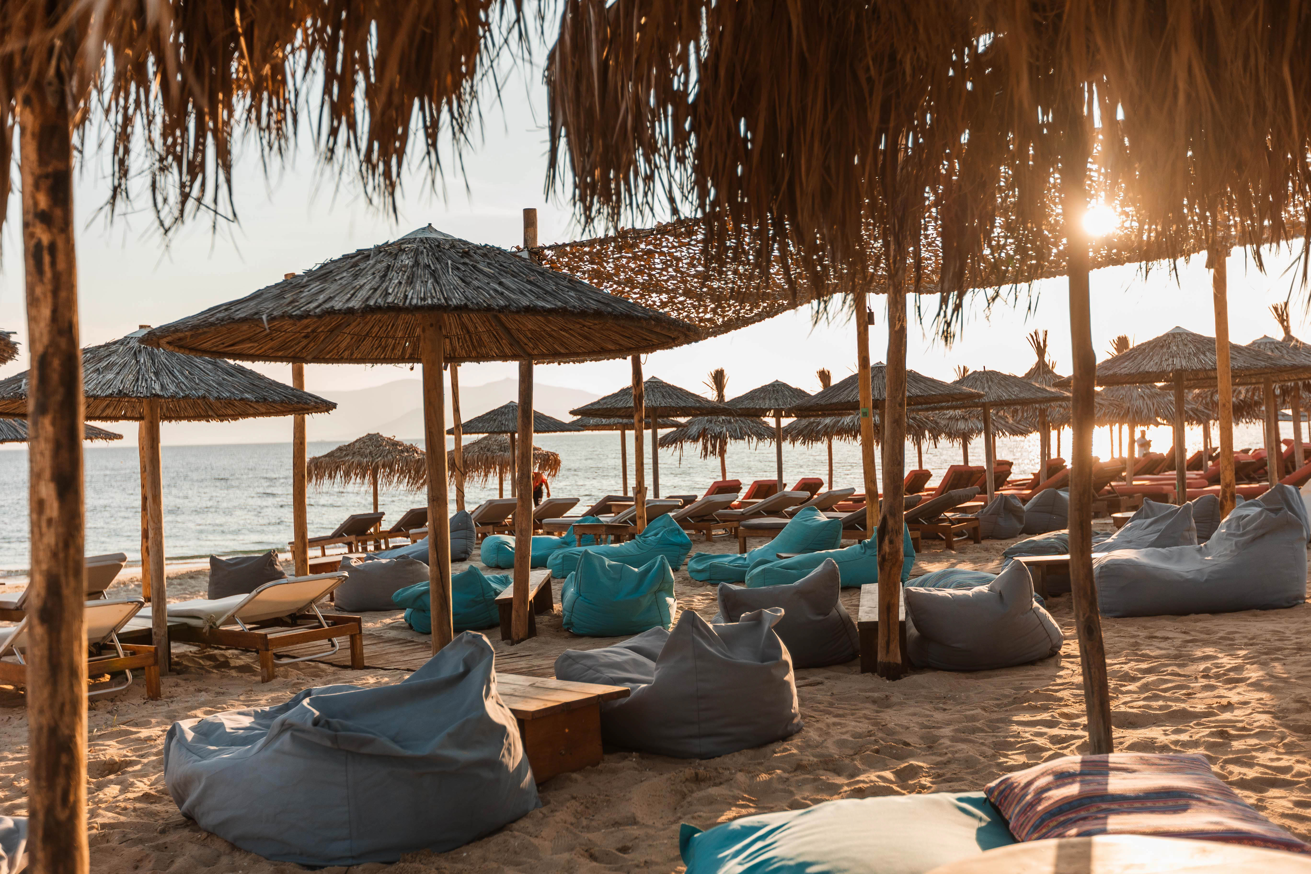 Thatched umbrellas and bean bags on the beach at golden hour, Naxos